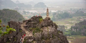 Rocky peak with a small pagoda above rice fields, showing best things to do in Ninh Binh.