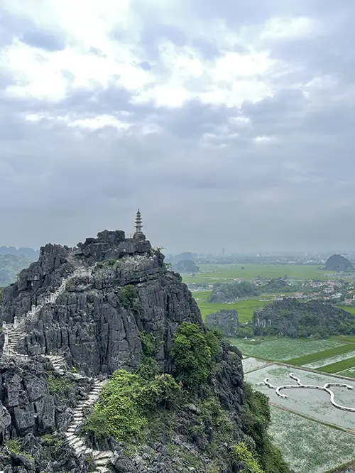 Climbing limestone karst viewpoint above rice fields, one of the top attractions in Ninh Binh.
