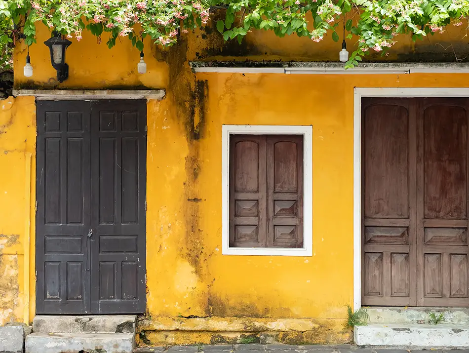 Weathered yellow house and closed doors along a narrow lane, showing Hoi An without the hype