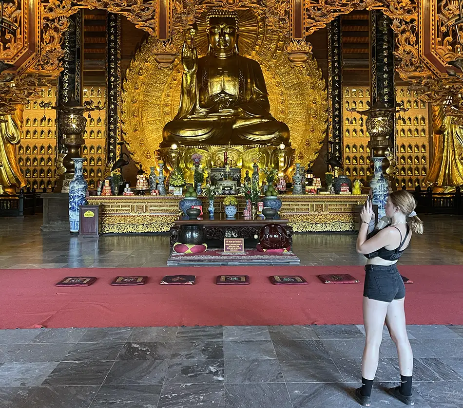Traveler wearing shorts and crop top inside Buddhist temple, showing how not to dress when visiting temples.