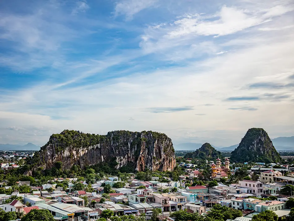 A wide view of the Marble Mountains rising above the surrounding town under a bright sky.