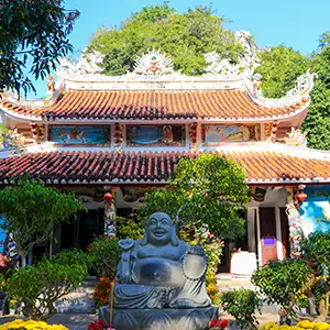A traditional pagoda framed by trees and statues in a peaceful courtyard.