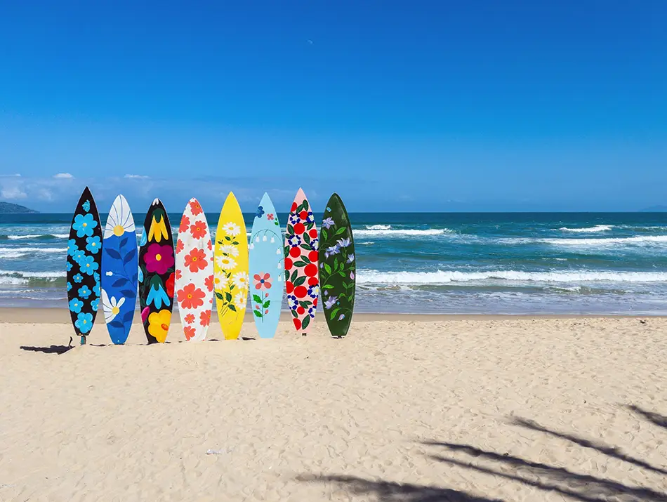 Colorful surfboards arranged on the sand ready for lessons at My Khe Beach.