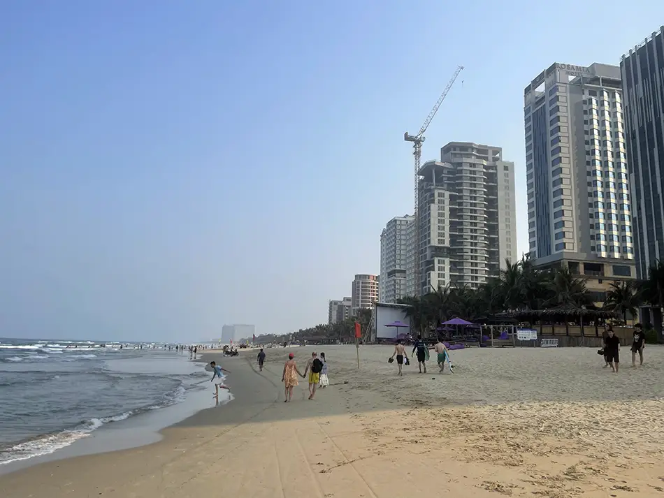 A stretch of My Khe Beach near the peninsula with buildings in the distance.