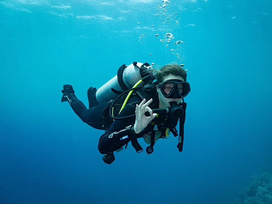 Scuba diver exploring underwater with clear blue water and bubbles rising around them, one of the top attractions on Phu Quoc island.