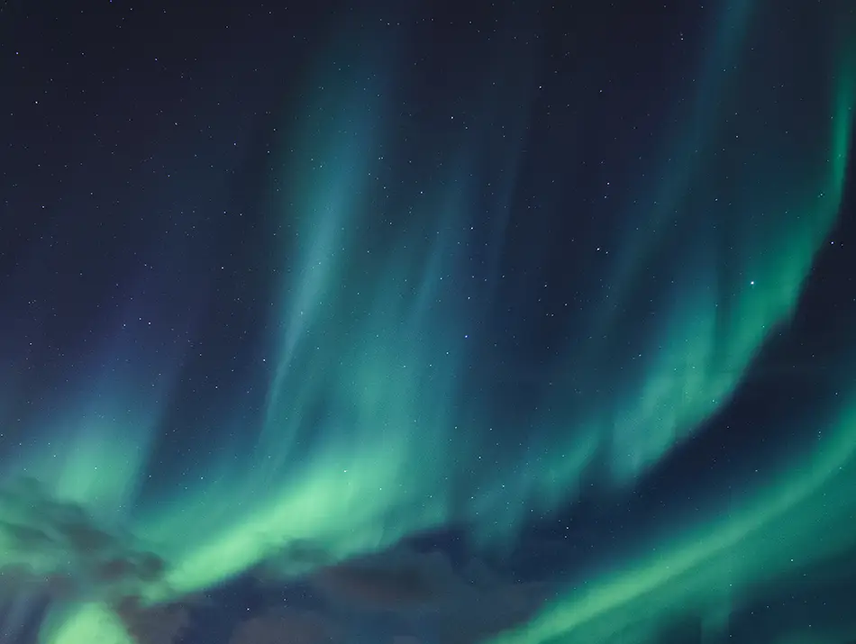 Sweeping green aurora curtains over Arctic tundra illustrate best places to see the northern lights.