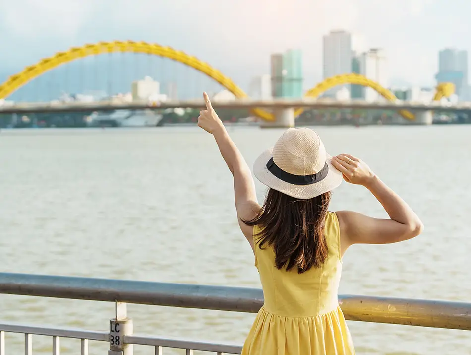 Traveler overlooking Dragon Bridge and Han River promenade in Da Nang, Vietnam.