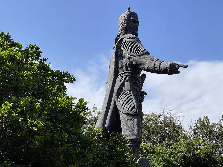 Bronze statue of Tran Hung Dao standing tall against the open ocean horizon.