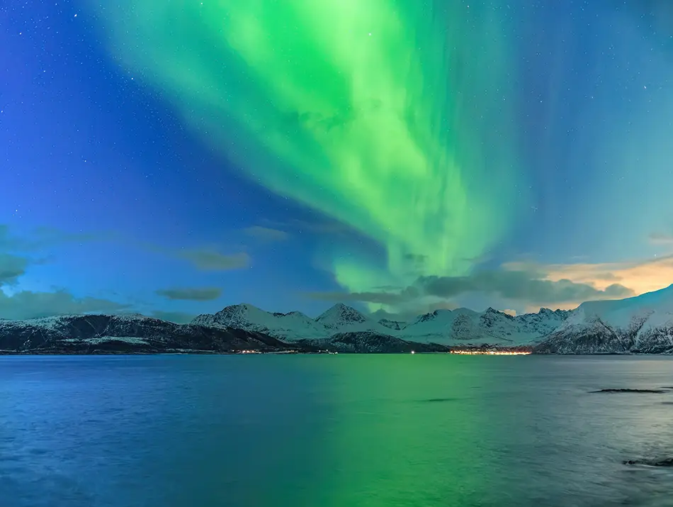 Emerald aurora reflected in a calm fjord near Tromsø highlights best places to see the northern lights.