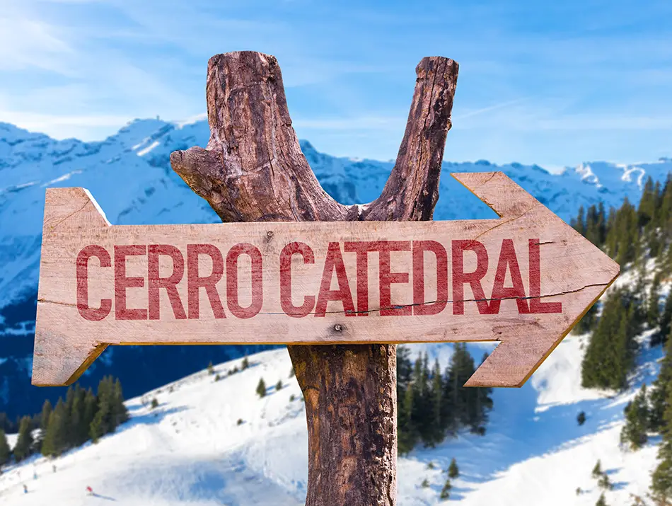 Wooden Cerro Catedral sign points toward peaks, a marker for hidden gem ski resort.