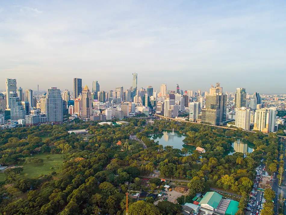 reen city park with a lake and skyline backdrop on a hazy morning.