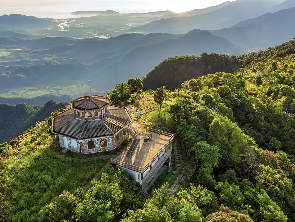 Hilltop pavilion surrounded by dense forest and rolling mountains inside a remote protected area.