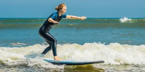 Rider standing on a soft-top board in small rolling waves, illustrating best surfing in Vietnam for beginners.
