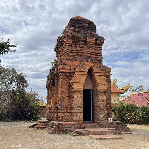 Historic Cham tower built from red brick on a hilltop.