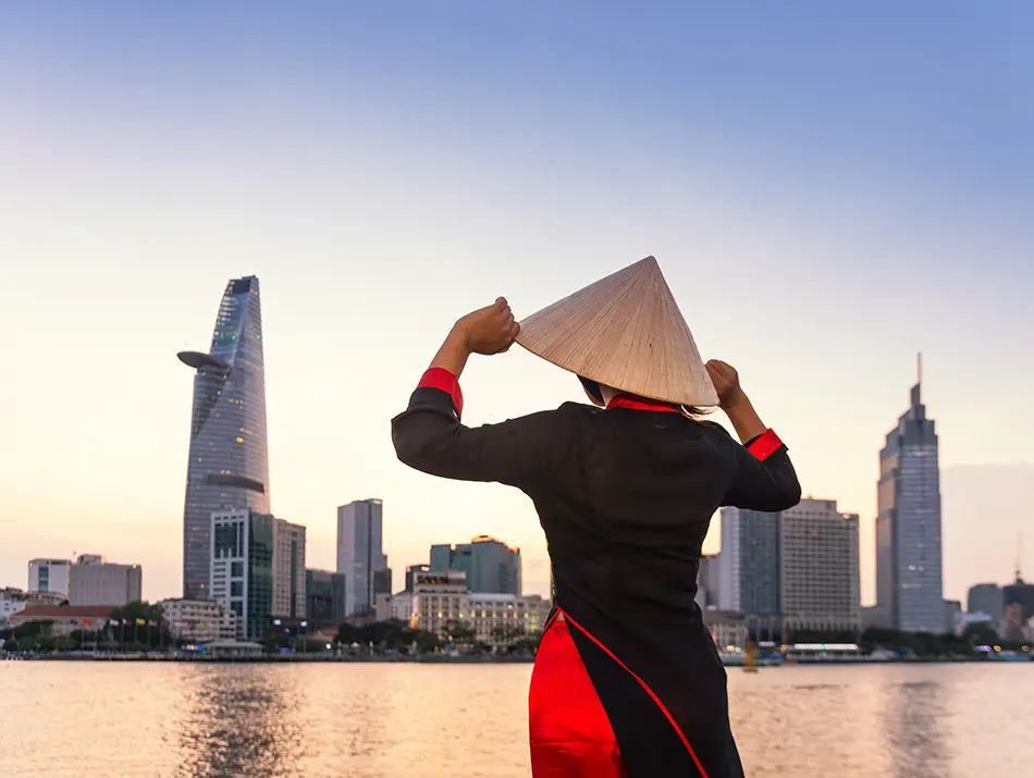 A traveler dressed in traditional dress overlooking the city-line highlighting the best things to do in Ho Chi Minh