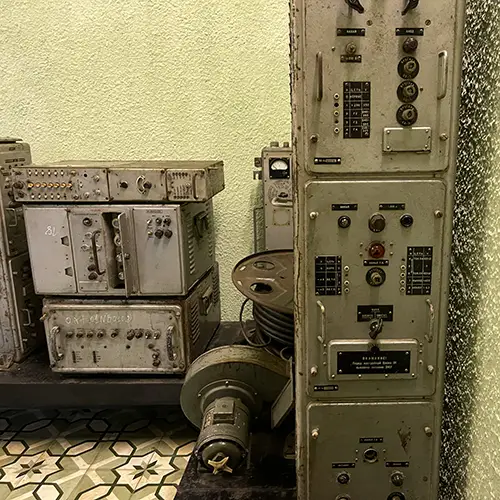 Vintage radio transmitters, metal control panels, and cables arranged inside a preserved underground room.