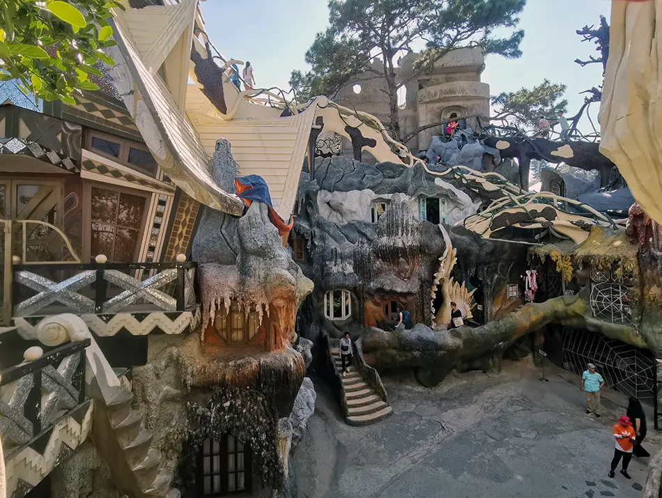 Surreal concrete architecture features twisted forms, balconies, and sculpted animal shapes.