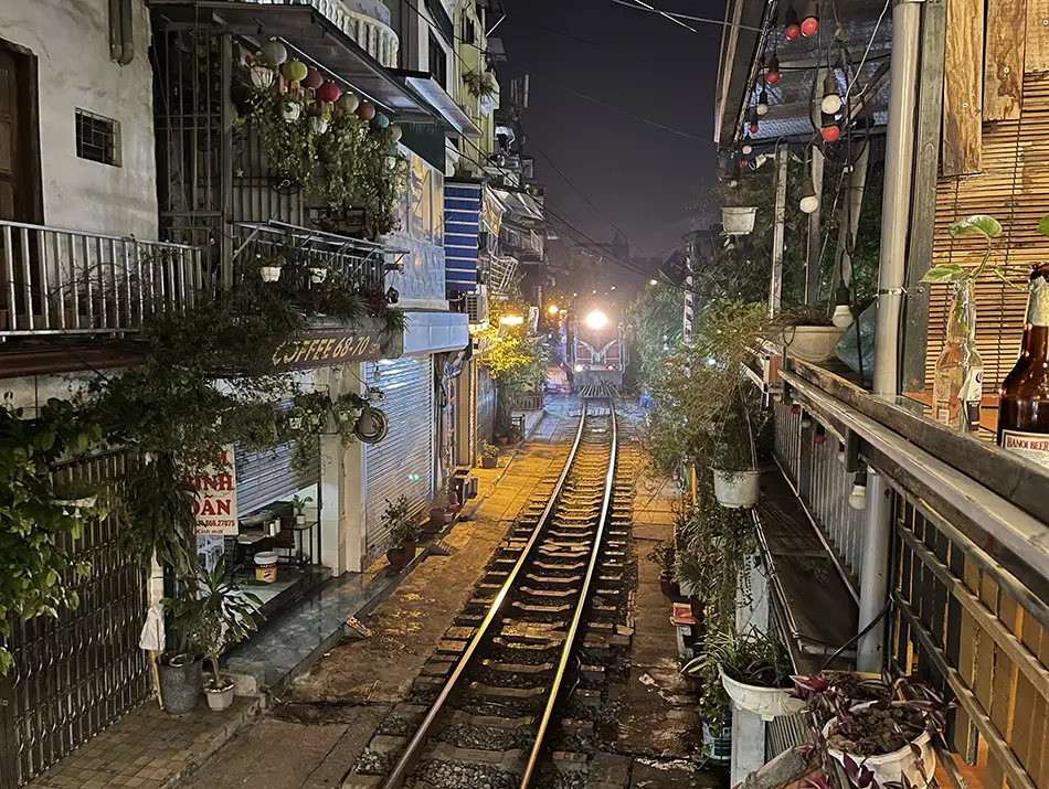 Small café counter and stools set directly beside active tracks at train street, a main tourist attraction in hanoi.