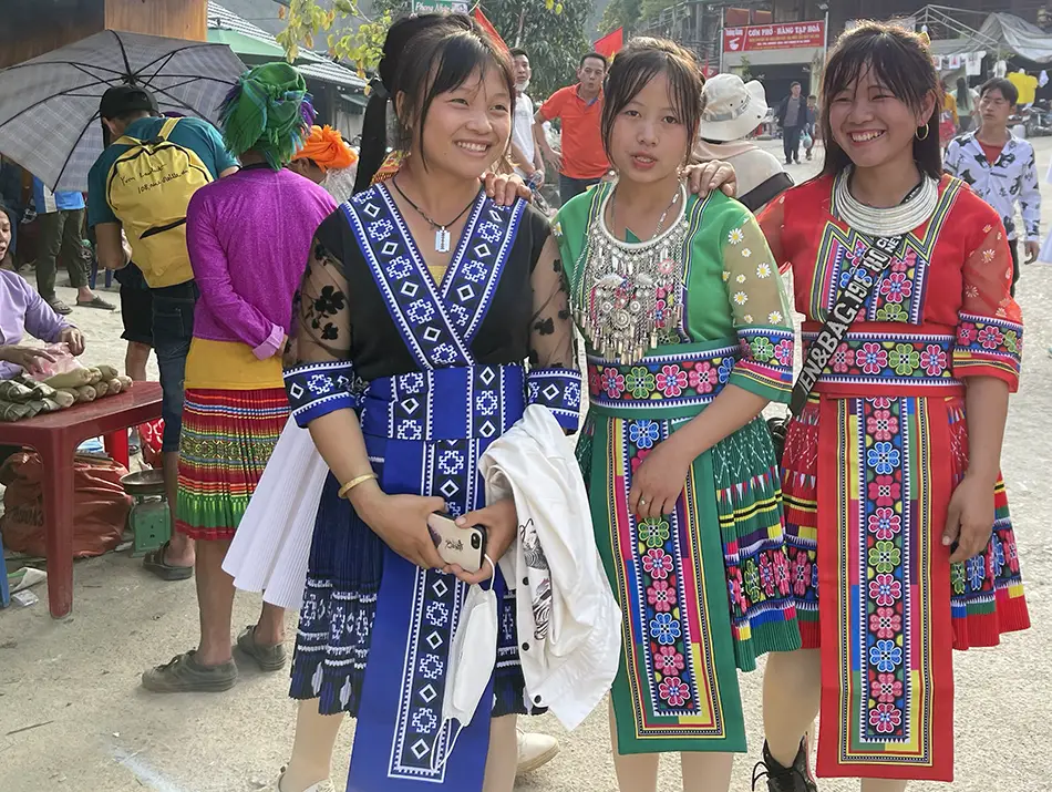 Women in colorful highland dress pose together after agreeing to be photographed, reflecting responsible travel in Vietnam.
