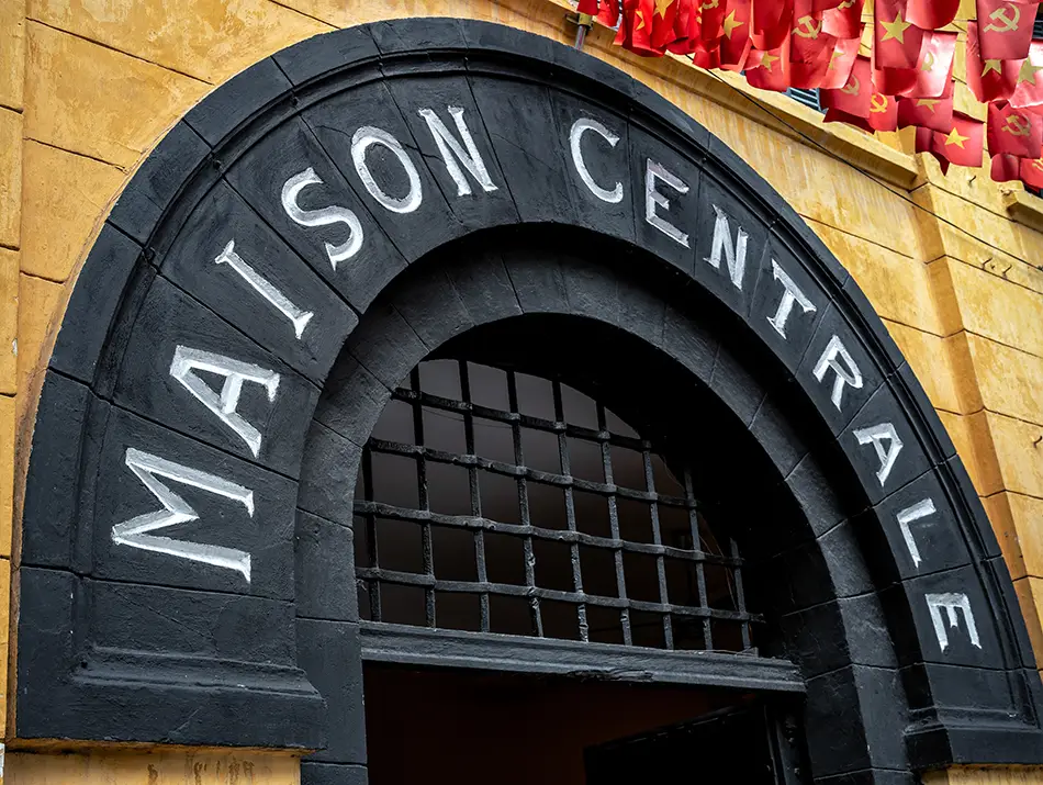 Stone arched entrance of Hoa Lo Prison with weathered walls.