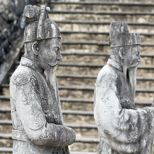 Stone guardian statues aligned along steep steps outside Khai Dinh Tomb entrance.