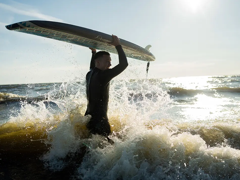 Surfer carries a board through shorebreak in La Libertad, El Salvador.