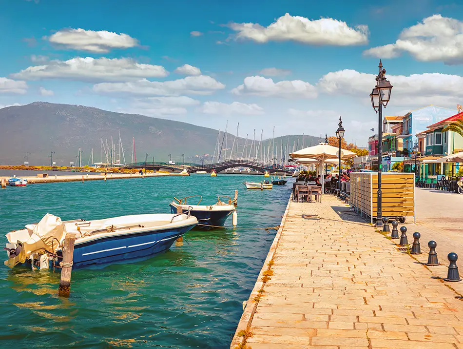 Harbor promenade with boats and colorful buildings in Lefkada town, Greece.