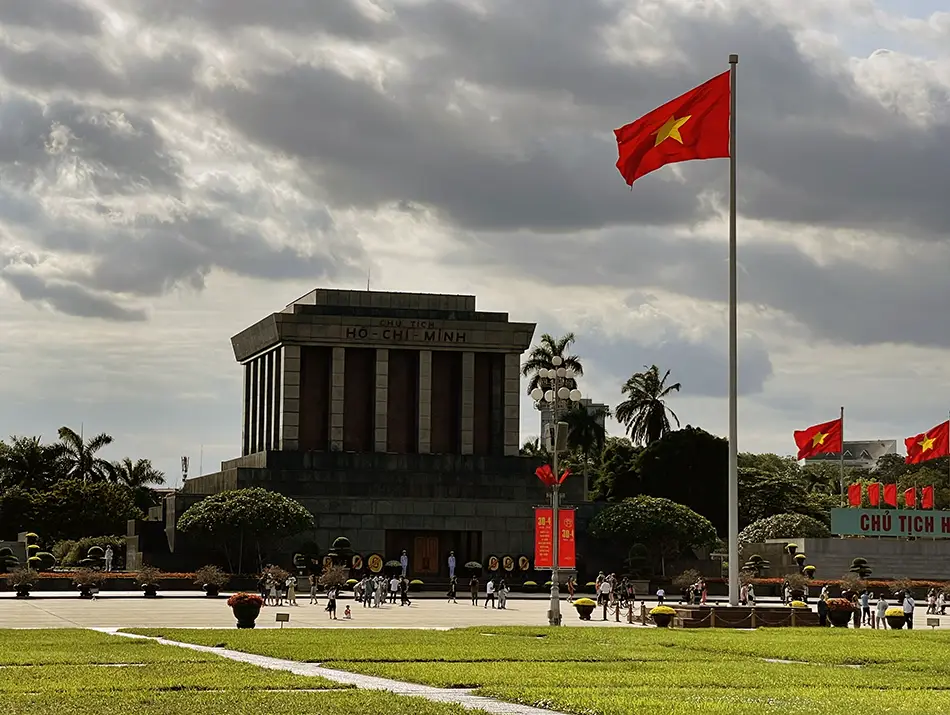 Large granite mausoleum facing an open square with visitors and guards standing formally.