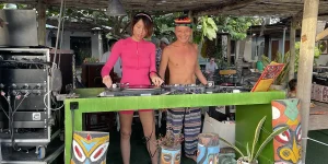 Two djs surrounded by speakers and tropical decor representing the beach side of vietnam nightlife