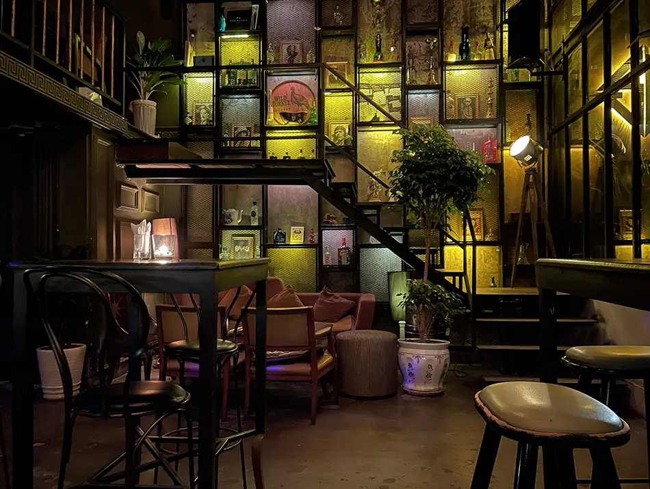 Moody Saigon bar with lantern shelves and stools.