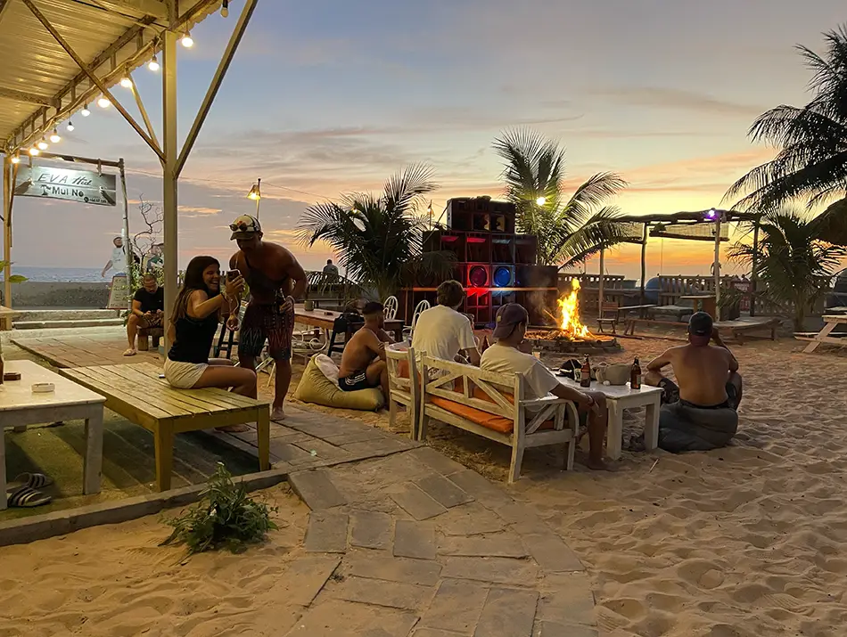 Sunset beach lounge with fire pit and daybeds, capturing Vietnam nightlife by the sea.