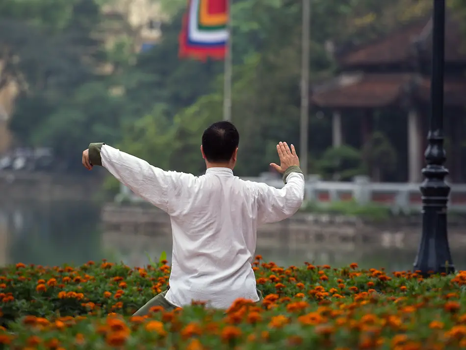 Local resident practicing tai chi near the water, reflecting some of the best things to do in Hanoi for cultural immersion.