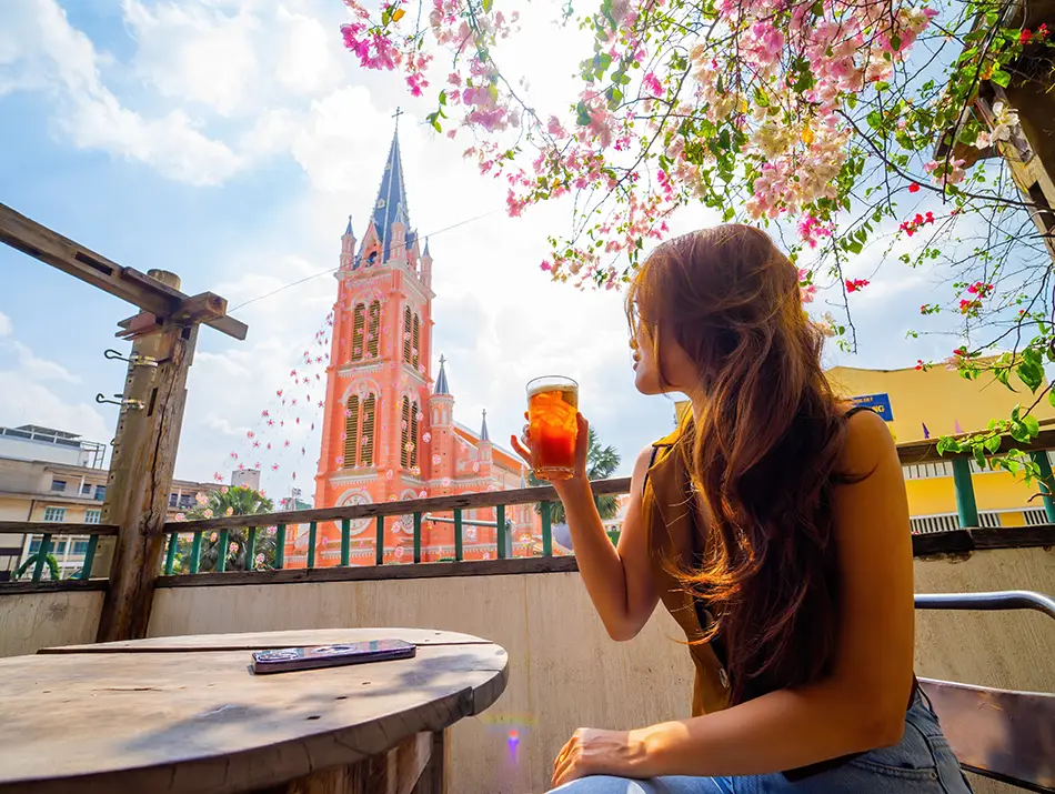 Woman sipping a cocktail on a terrace with pink church view