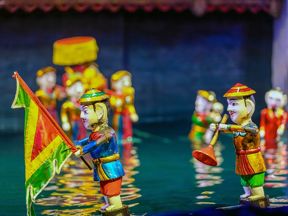 Colorful wooden puppets performing on water with musicians during a traditional stage show.