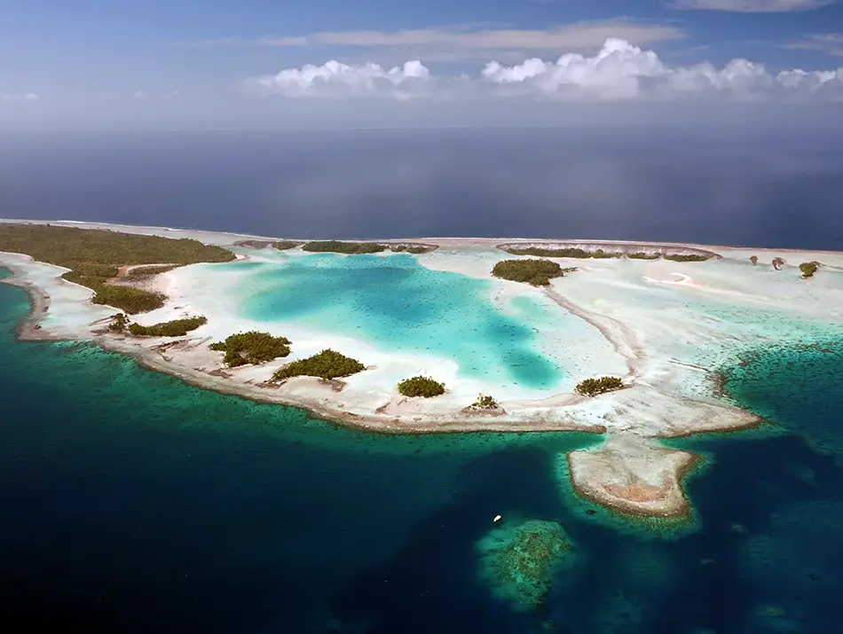 Aerial view of a turquoise atoll lagoon with coral shallows and reef rings.