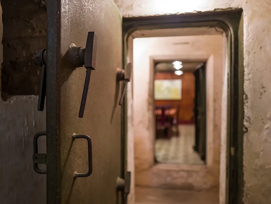 Narrow concrete corridor with maps and equipment inside a preserved underground military bunker.