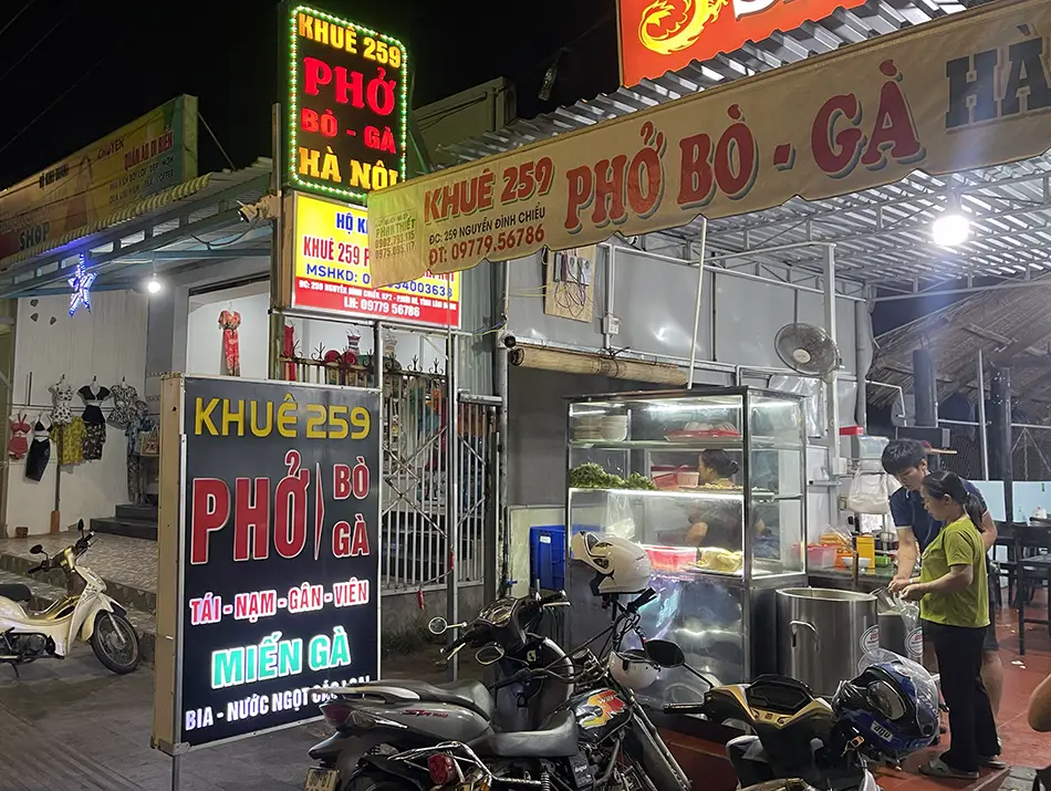 Streetfront sign for a 24-hour pho bo shop, best places to eat in Mui Ne after midnight.