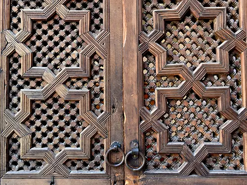 Carved cedar panel with geometric motifs and aged patina in close-up.