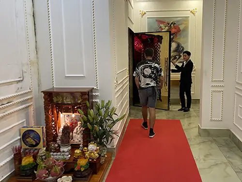 Guests walking along a red carpet inside an ornate entrance corridor.
