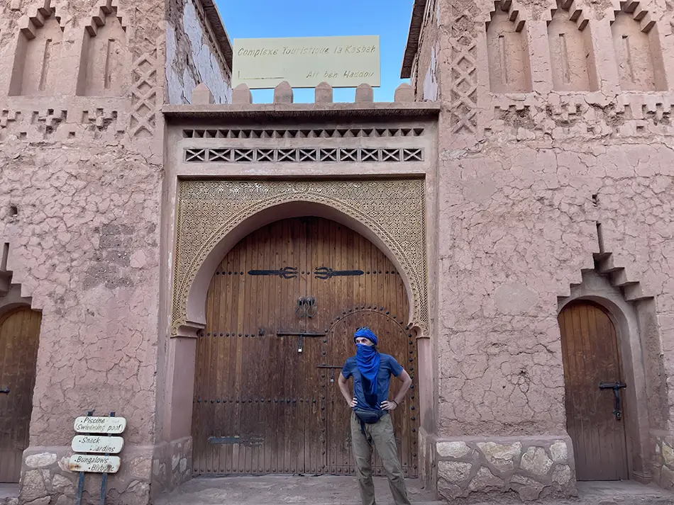 Traveler standing beneath carved adobe archway at Ait Ben Haddou, Morocco. Probably number 1 jet setting destination.