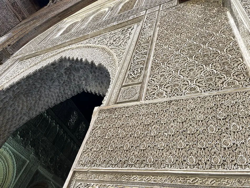 Intricate carved stucco and muqarnas arch inside the madrasa in Fes