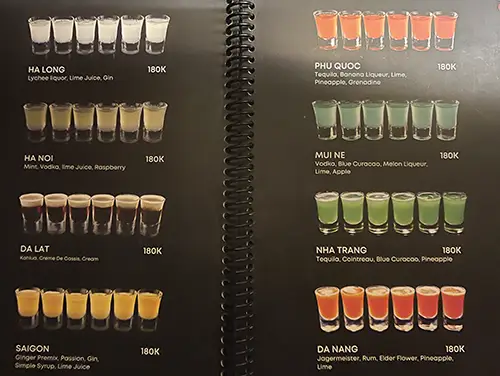 Backlit drinks menu board listing cocktails and shot options inside the venue.