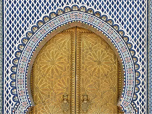 Intricate brass door patterns and carved cedar framing the palace entrance.