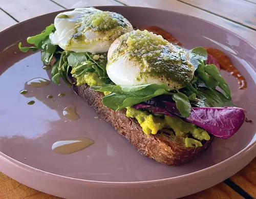 Avocado toast topped with eggs and greens, popular at Vegan-friendly restaurants.