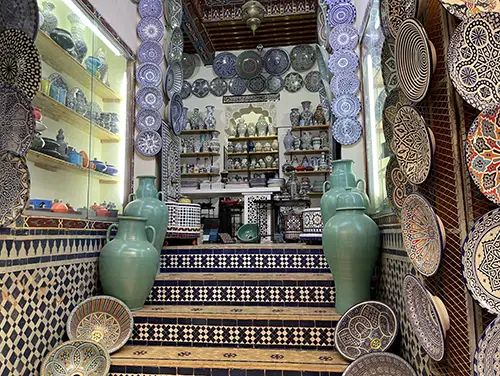 Stacked pottery and mosaic plates displayed inside a ceramic shop.