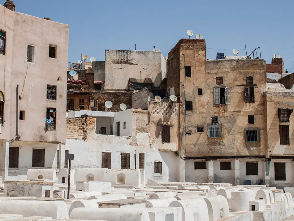 Whitewashed cemetery with simple tombs near Ibn Danan Synagogue.