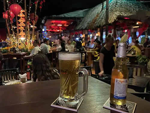 Two beers on a wooden table at Joes Bar, a familiar scene in Mui Ne Nightlife.