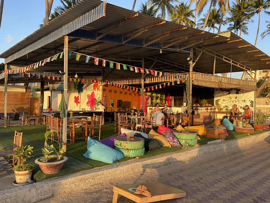 Open-air seating area with low cushions and colorful flags at The King Bar in Mui Ne.