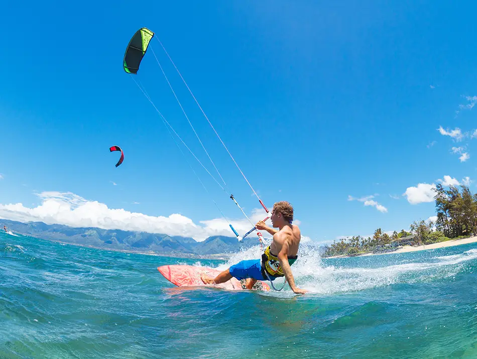 Experienced kitesurfer carves across choppy water with mountains in the background.
