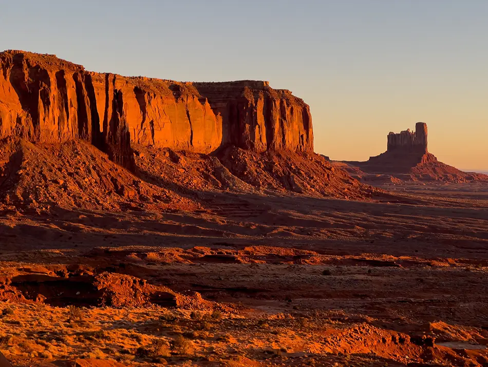 Golden sunrise illuminating sandstone buttes in Monument Valley, USA.